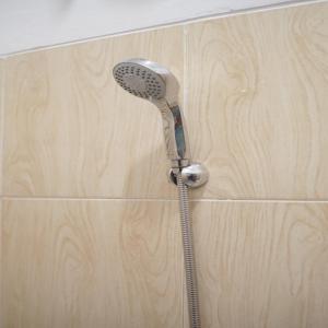 Un cabezal de ducha está colgado en una pared de madera. en Hotel Permata Zamrud, en Cirebon