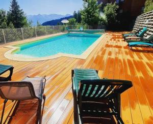 a swimming pool on a wooden deck with chairs around it at Appartement 4-6 personnes à Puy-Saint-Vincent in Puy-Saint-Vincent