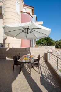 een tafel en stoelen met een parasol op een terras bij Katerina Apartment in Afantou +24 foto's