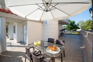 een tafel en stoelen met een parasol op een terras bij Katerina Apartment in Afantou
