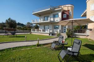 a table and chairs with an umbrella in front of a house at Katerina Apartment in Afantou