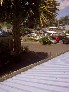 a palm tree next to a parking lot with cars at Lovely 1 bedroom apartment in Grand Bay, around 5 mins walk to the beach in Grand Baie +3 photos