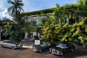 three old cars parked in front of a building at Viroth's Hotel in Siem Reap