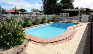 a swimming pool with a brick walkway around it at Harvest Lodge Motel - Gunnedah in Gunnedah