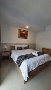 a bedroom with a large bed and a picture on the wall at ADIJAYA Canggu in Kerobokan