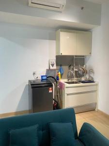 ein Wohnzimmer mit einer blauen Couch und einer Küche in der Unterkunft Cozy Unit and Walking distance to MRT in Sungai Buloh