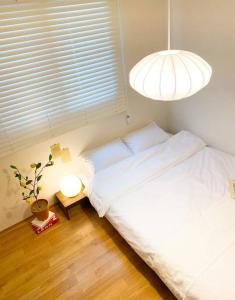 Un dormitorio con una cama blanca y una lámpara. en Aju stay Geoje, en Geoje
