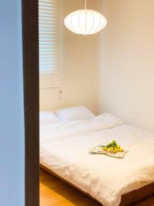 Una cama blanca con un plato de fruta. en Aju stay Geoje, en Geoje