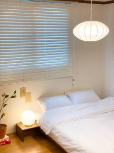 Un dormitorio con una cama y una lámpara y una ventana. en Aju stay Geoje, en Geoje