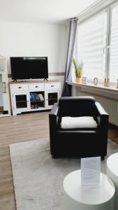 a living room with a black couch and a tv at Ferienwohnungen Naturzeit in Willingen