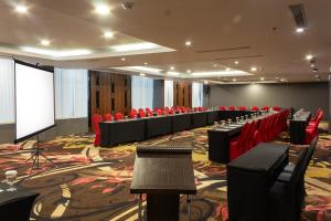 a conference room with red chairs and a screen at Aston Gorontalo Hotel & Convention Center in Gorontalo