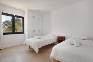 a white room with two beds and a window at Finca Ses Rotes in Cala Ferrera +32 photos
