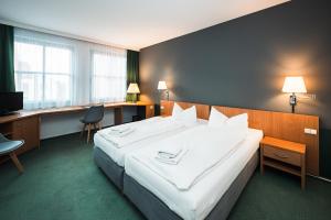 a hotel room with a large bed and a desk at martas Hotel Lutherstadt Wittenberg in Lutherstadt Wittenberg