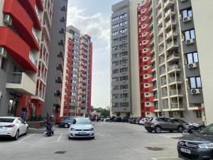 a parking lot with parked cars and tall buildings at Iulius Mall Area Apartament in Iaşi