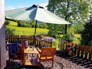 a table and two chairs with an umbrella at Beavers Lodge on top of the Shropshire hills in Craven Arms