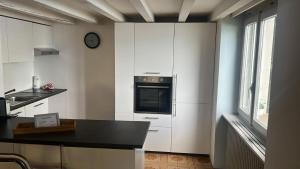 a kitchen with white cabinets and a clock on the wall at Dream Apartment Room lake 3 in Paradiso