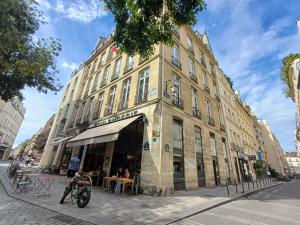 a building on a street with people sitting at tables in front at Happy Stay Paris - Suite Hotel de Ville le Marais in Paris