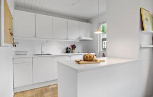 a white kitchen with white cabinets and a bread on a cutting board at Awesome Home In Gilleleje With Kitchen in Gilleleje