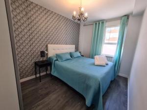 una camera da letto con un letto con lenzuola blu e una finestra di Dos Torres Ribera Play & Relax con Jacuzzi y cine a Saragozza