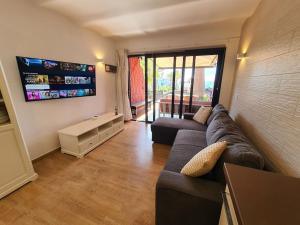 a living room with a couch and a flat screen tv at Vivienda Vacacional frente al mar Playa del Aguila in Playa del Aguila