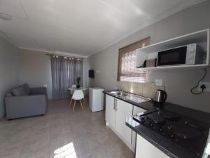 a kitchen and living room with a couch and a microwave at khutsong Apartments in Secunda