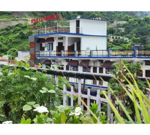 a white building with a blue balcony at Hotel Omkaar & Restaurant Chinyalisaur in Chhām