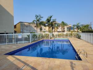 a swimming pool with a fence and palm trees at Apartamentos Gratitude in Ubatuba