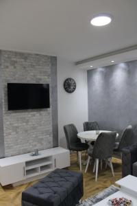 a living room with a table and a tv on a brick wall at IN SILVER Apartman in Vršac