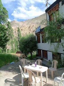 a white table and chairs in front of a building at Green Land Guest House Ladakh by LexStays in Lāmayūrū