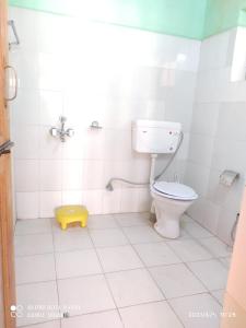 a bathroom with a toilet and a yellow stool at Green Land Guest House Ladakh by LexStays in Lāmayūrū