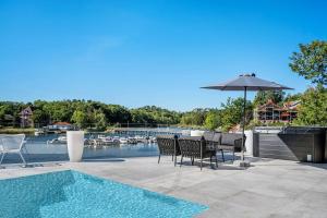 a patio with chairs and an umbrella and a swimming pool at Lyxig villa i Solsidan in Stockholm