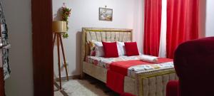 a bedroom with a bed with red sheets and a red curtain at One Bedroom Bamburi in Mombasa