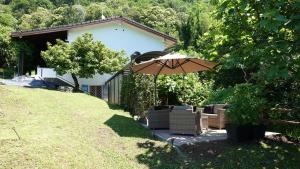 a patio with an umbrella and chairs in a yard at BBPrimavera in Purasca