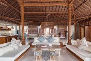 Una sala de estar abierta con sofás y mesas blancos. en Dolce Vita Nusa Penida, en Nusa Penida
