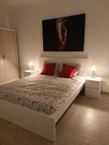 Un dormitorio con una cama grande con dos almohadas rojas. en La Casa de Aba, en Telde