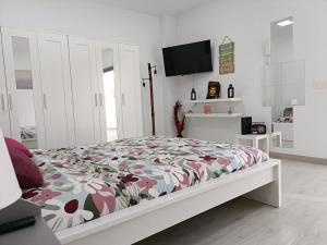 Un dormitorio blanco con una cama con un edredón floral. en La Casa de Aba, en Telde