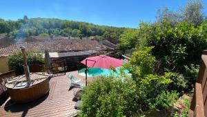 una terrazza in legno con ombrellone e piscina di Gîte Chez Nanou & Ju, Ste Croix Volvestre a Sainte-Croix-de-Volvestre