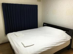 a white bed in a room with a blue curtain at Kaku in Furano