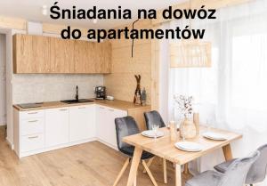 a kitchen with a wooden table and chairs and a table at Apartamenty Grapa Resort 2xSauny 2xSale zabaw Balia Kulkolandia in Białka Tatrzańska