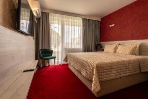 ein Schlafzimmer mit einem Bett und einer roten Wand in der Unterkunft Hotel Dorna in Mamaia
