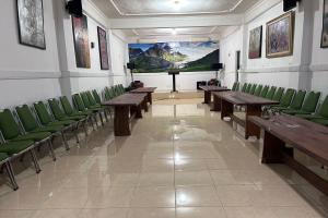 a conference room with wooden tables and green chairs at Hotel Kinasih Yogyakarta in Yogyakarta