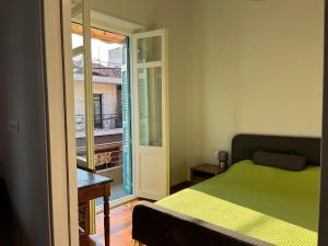 a bedroom with a green bed and a balcony at Edipsos Serenity Suites in Loutra Edipsou