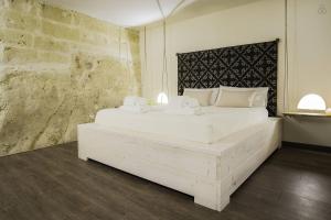Cette chambre comprend un grand lit blanc et un mur en briques. dans l'établissement Il Vento dei Sassi, à Matera