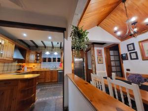 a kitchen with wooden cabinets and a bar with white chairs at Orotava Garden House perfect for families in La Orotava +35 photos