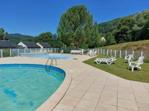 a swimming pool with two chairs and a table and a picnic table at Chez Maïka et Etienne in Saint-Geniez-dʼOlt