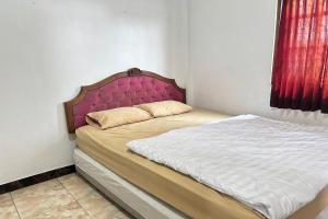 a bed with a pink headboard in a bedroom at Hotel Kinasih Yogyakarta in Yogyakarta