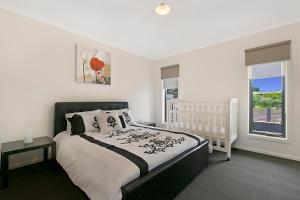 a white bedroom with a bed and a window at Palm Grove Beach House Dromana in Dromana