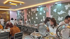 a group of people sitting at a table eating food at Hotel Gridhakuta International in Rājgīr