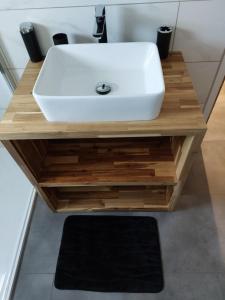 ein Badezimmer mit einem weißen Waschbecken auf einem Holztisch in der Unterkunft La maison du bonheur in Saint-Médard-en-Jalles