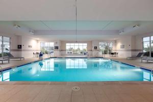 a large swimming pool with blue water in a building at Hilton Garden Inn Milwaukee Northwest Conference Center in Milwaukee